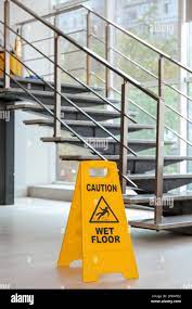 Cartello di sicurezza con la frase attenzione pavimento bagnato vicino alle scale. Servizio di pulizia Foto stock - Alamy