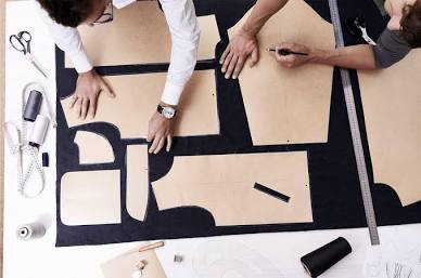 Manual pattern drafting on a factory cutting table, AI generated