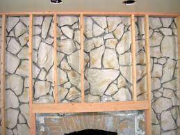 A fireplace clad with grey patterned tiles and reclaimed wood over it to keep it safe How To Build A Standard Wall Over A Stone Wall Stone Fireplace Makeover Cover Stone Fireplace Stone Fireplace Wall