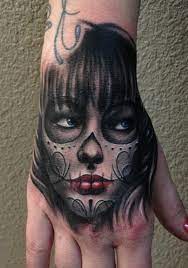 These days, a sugar skull tattoo is getting to be popular for both men and women. Day Of The Dead Hand Tattoo Dia De Los Muertos By Carl Grace Tattoos Hand Tattoos Sugar Skull Girl Tattoo