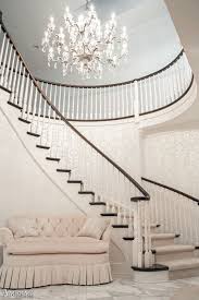 crystal chandelier over a charming curved wood staircase featuring designer wallpaper love seat building design curved staircase staircase design