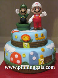 The top level being a yellow star, middle level iconic mario clouds with eyes, a grass bottom teir, and classic mario kart stripy baseboard. 7 Mario Cakes For Boys Photo Kids Birthday Cakes Mario Kart Birthday Cake And Super Mario Brothers Birthday Cake Ideas Snackncake
