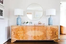 Blue Lamps Light A Round Brass Mirror Hung Over A Burl Wood Credenza Burled Wood Furniture Credenza Decor Wood Credenza