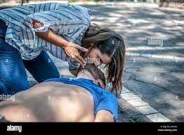 girl helping an unconscious guy with mouth to mouth resuscitation and cpr  Stock Photo - Alamy