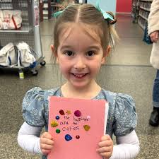 title 6-year-old Pia dressed up to come in last Saturday to show off her  first book! It's called The Hamsters and the Cuties in Numshkinland, and  her dad said she worked hard