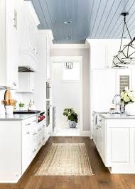 A Grosvenor Linear Triple Pendant Hangs From A Blue Plank Ceiling Over A White Kitchen Island Boasting A Fa Kitchen Ceiling Black Kitchen Faucets Plank Ceiling