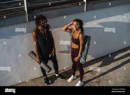 Smiling yuong healthy african couple with fitness mats standing outdoors  Stock Photo 