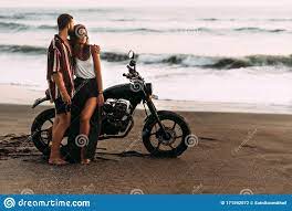 Pareja En Moto En La Playa Una Pareja Enamorada De La Playa Se Encuentra Con La Puesta De Sol Un Hombre Abraza A Una Mujer En La Foto De Archivo Imagen