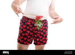 Horny guy wearing his underwear, with Christmas mistletoe tied over his  boxer shorts. White background Stock Photo - Alamy