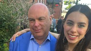 a man in a blue jacket stands next to a woman in a black dress