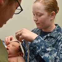 Kim Baughman, a registered nurse at the Naval Hospital Jacksonville  maternal infant unit, checks a newborn's reflexes.