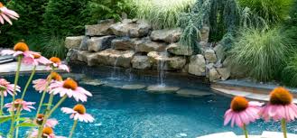 A large decorative rock wall showcases an assortment of waterfalls with a small grotto, while a waterslide winds through the rocks creating a fun environment for kids and. Pool Waterfall Ideas Nj Transform Your Backyard