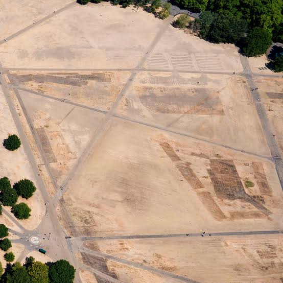 Aerial view of a dried-up riverbed in Europe during a severe heatwave, showing scorched earth and stranded vessels.