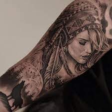This colorful neck piece has the face of a tribal woman with long feathers and a braided tail. 60 Tatuagens De Indios Que Sao Incriveis Native American Tattoo Designs Native American Tattoo Native American Tattoos