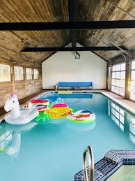 Indoor Pool With Reclaimed Fence Wood Lining The Inside Commercial Glass Garage Doors Black Metal Beam Indoor Pool House Pool House Plans Indoor Outdoor Pool