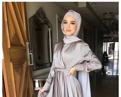 Gambar young woman wearing a formal hijab outfit with a satin hijab, long dress, and jewelry