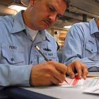 Electricians Mate 2nd Class Kurtis Chesley from, Pembroke, N.H., instructs  Rear Adm. Andrew Lewis, commander of Carrier Strike Group (CSG) 12,
