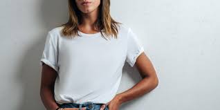 Portrait Of Blond Woman Wearing White T-Shirt In Front Of Light Wall  Looking Up Stock Photo