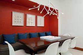 Bright pink feature wall in dining room with wooden table and red artwork plants and drawers. How To Create A Sensational Dining Room With Red Panache