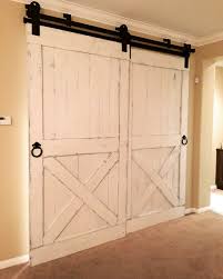 If you're like us and have always loved the look of a barn door, but you're intimidated by the thought of hanging or building it, this tutorial is for you. Distressed White Barn Doors With Bypass Hardware For A Bar Room Interior Barn Doors Barn Doors Sliding Red Barn Door
