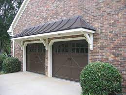 But, of course, sometimes a cheap roof is all we can afford. Metal Roof Bracket Portico Over Double Garage Doors Designed And Built By Georgia Front Porch Garage Door Design Garage Doors Door Overhang