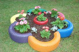 Firstly what you need is dig a big hole on the ground on your garden, the size most suitable for your tire and make sure your tire fits perfectly in the hole and put it there. Flower Bed Made From Old Tires And Small Tire In The Center Diy Garden Decor Tire Garden Flower Planters