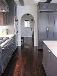 This is a very modern looking kitchen, one that sports dark oak wood floors. Arched Entry Way Out Of A Kitchen With Dark Grey Cabinets And Drawers Marble Counter Tops White Cabinets Kitchen Dark Floors Dark Grey Kitchen Grey Flooring