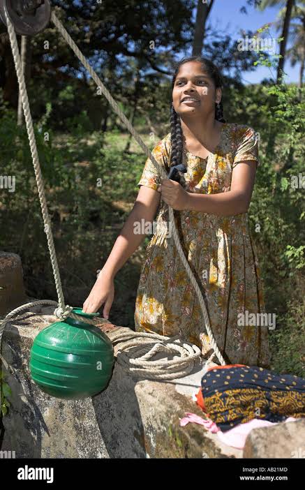 Young woman draws water from well by hand with green pot on traditional rope pulley Mandrem village Goa Stock Photo - Alamy