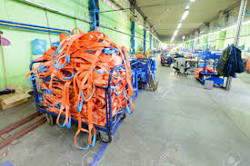 Taller De Costura Para La Producción De Nylon Correas De Sujeción.  Contenedor De Malla De Metal Con Eslingas De Carga De Naranja Suave. Fotos,  Retratos, Imágenes Y Fotografía De Archivo Libres De