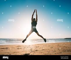 Jumping Man Young Fitness Man Doing Jumping Jacks Or Star Jump Exercise On The Beach Stock Photo Alamy