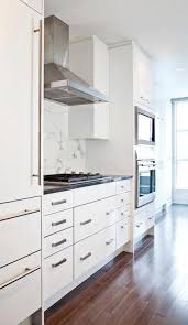 Sleek White Kitchen With White Flat Front Cabinets Accented With Brushed Nickel Pulls And Black C Kitchen Cabinets White Modern Kitchen Kitchen Bar Stools Diy
