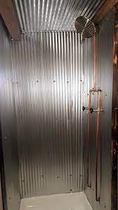 Corrugated tin installation usually takes little time due to the large sheet size, but the tin must be sealed on the edges and between each sheet to prevent water from splashing or running between the tin and the wall. Tiny House For Sale Custom One Of A Kind Tiny Home Tin Shower Walls Cabin Bathrooms Rustic Bathrooms