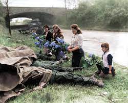 Three young Russian women and a little girl recently liberated from a slave- labor camp by the U.S. Army lay flowers at the feet of four dead American  soldiers, April 18, 1945, Hilden,