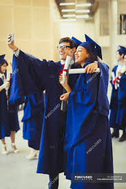 Group of ecstatic graduates with diplomas. College Graduates In Cap And Gown With Diplomas Taking Selfie Incidental People Togetherness Stock Photo 200692914
