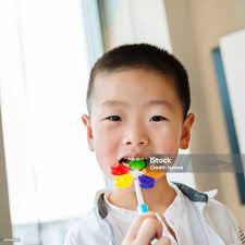 Little Asian Boy Eating A Colorful Candy Stock Photo
