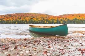 Canoa en la orilla de un lago, ajuste de la naturaleza del otoño ...