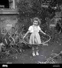 1960Er, Historisch, Draußen Auf Einem Gartenweg, Ein Kleines Mädchen Mit  Einem Hula Hoop Reifen, Einem Spielzeugreifen, Um Ihre Taille, Deutschland.  Obwohl Es Den Hula Hoop Reifen Schon Seit Hunderten Von Jahren Gab