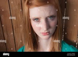 Fifteen year old girl with red hair and green eyes looks at camera with  upset expression Stock Photo