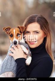 Jeune femme tenant son chien de terrier Jack Russell portant des vêtements  chauds d'hiver sur les mains Photo Stock