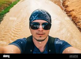 Male hiker prend un auto-portrait avec son téléphone cellulaire en face  d'une grotte de glace du glacier Gulkana;Alaska, États-Unis d'Amérique  Photo Stock