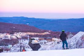 Young female snowboarder riding snowboard on copy space background of clear bright blue sky and snowy mountains on sunny winter day. Beech Mountain Ski And Snowboard