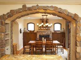 Interiors shots of a modern apartments in the foregorund the glass dining table with a vase of flowers overlooking on large luxury dining room interior with kitchen and arch. Country Dining Room With Stone Arch Cottage Dining Rooms Archways In Homes Modern Houses Interior