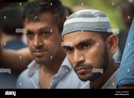 Saif Akonjee, son of Imam Maulana Alauddin Akonjee, center, Mashuk Uddin,  brother of Thara Uddin, right, and other members of the community are  surrounded by reporters as they arrives to a Queens