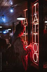Check out our artwork and request a free consultation. Woman Looking Her Phone At Night In Front Of A Tattoo Shop By Thais Ramos Varela For Stocksy United Tattoo Shop Tattoo Studio Tattoo Salon