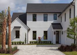 Black And White Exterior Modern Homes Modern Farmhouse With White Stucco Black Windows And Black Roof Modern Farmhouse With White Stucco Black White Stucco House Stucco Homes House Paint Exterior