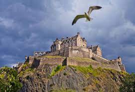 Das foto zeigt eine weite aufnahme von edinburgh stadt, einschließlich edinburgh castle in orange beleuchtet und andere bemerkenswerte edinburgh wahrzeichen. Schottland Edinburgh Castle Geo