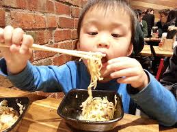 Isaac eating ramen with chopsticks at Shyun Ramen Bar, Car…