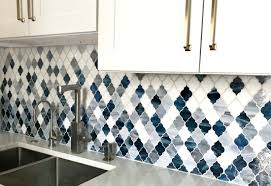 A white kitchen with a grey tile backsplash and a blue kitchen island plus white stone countertops is chic. Customize An Existing Pattern Edgewater Studio Artisan Tile