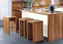 En este caso la barra de madera está dedicada a la zona del comedor ya que hay otra encimera más. Cocina En Linea En Magnolia Con Barra Y Taburetes En Madera De Almendro