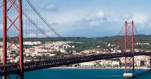 Un uomo estremamente religioso sta pregando su una spiaggia toscana. Ponte 25 De Abril A Construcao Mais Imponente De Portugal